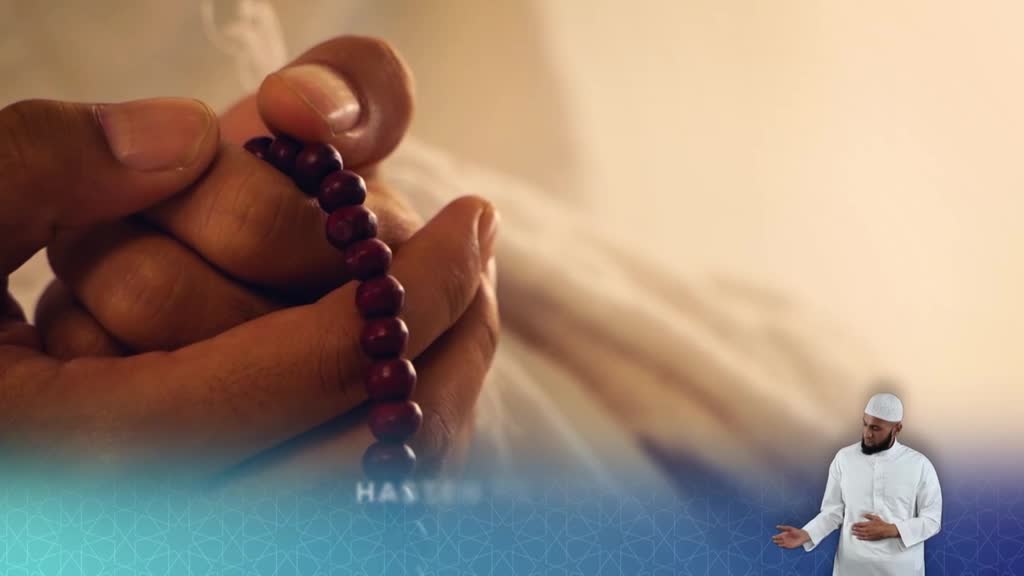 A hand gently holds a string of dark beads, the thumb and forefinger carefully turning them. In the corner, a man in a white thobe gestures while speaking, likely on the Islam Channel in the United Kingdom.
