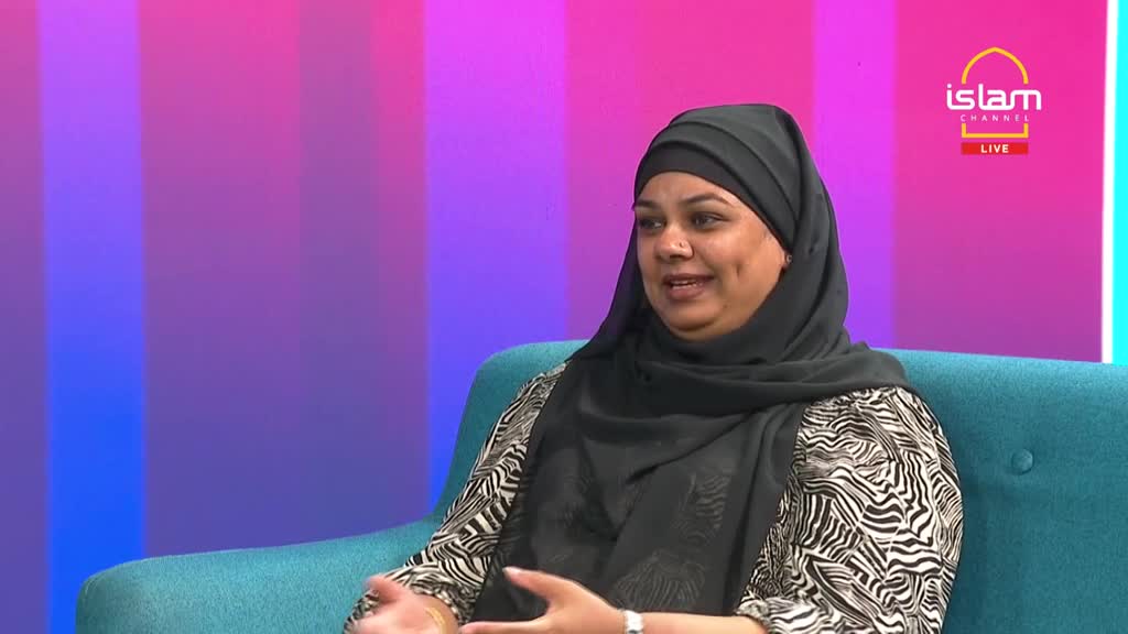 A woman wearing a black hijab sits on a teal couch, speaking animatedly. Her hands are gesturing as she talks, and the Islam Channel logo is visible in the background.
