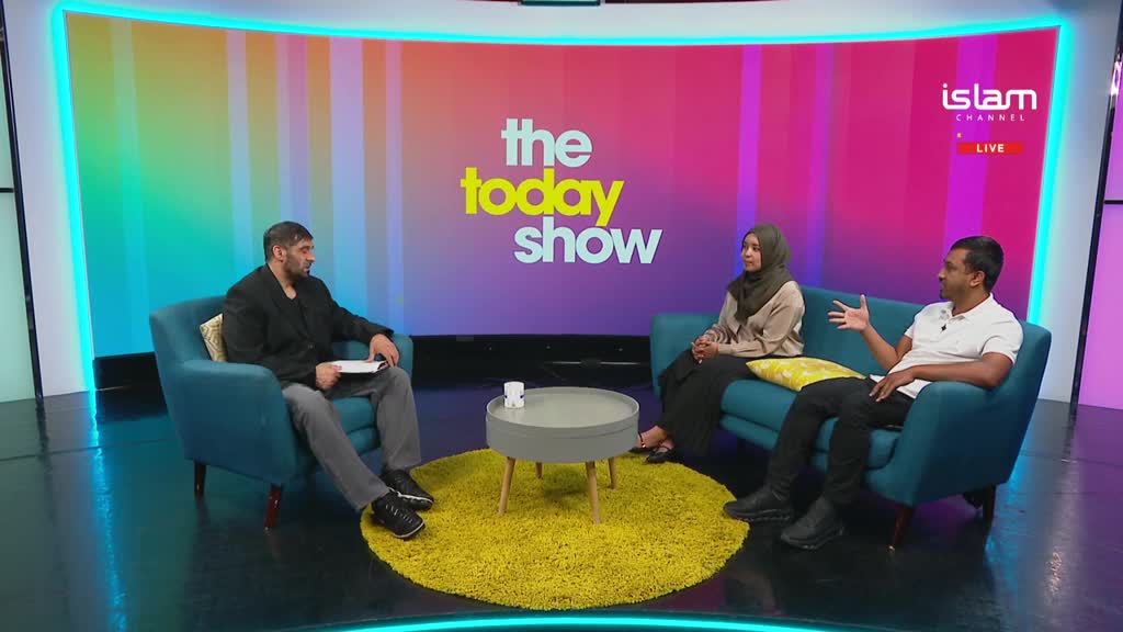 Three people are seated, engaged in conversation on a television set, with the "Islam Channel" logo visible. The man on the right gestures with his hand, while the person on the left holds a notepad.
