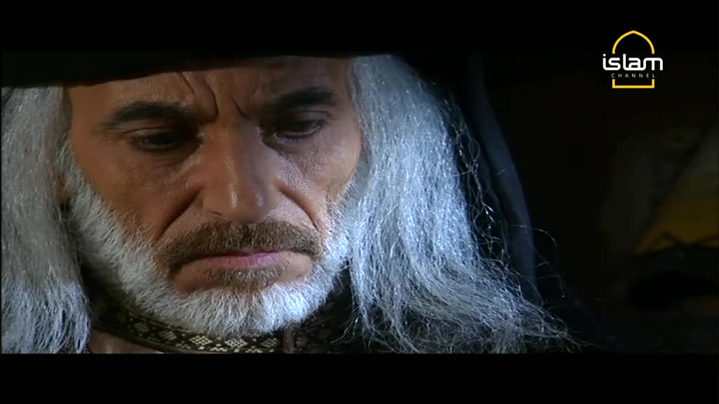 A man with long, white hair and a matching beard stares downward, his expression somber. The Islam Channel logo is in the corner, suggesting this is a scene from a broadcast.
