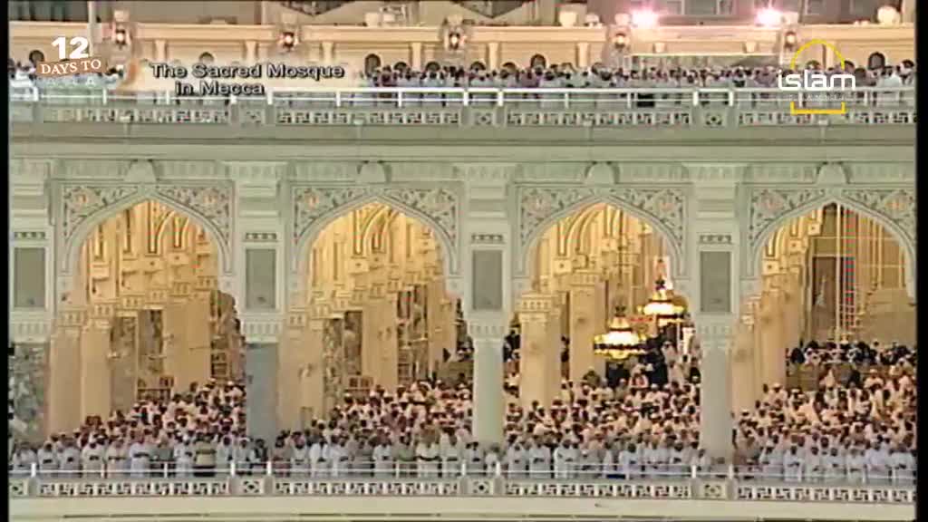 Thousands of people in white garments fill the courtyard of the Sacred Mosque in Mecca. Ornate arches and columns frame the scene, with a broadcast from Islam Channel visible in the upper right corner, indicating the countdown to an event.