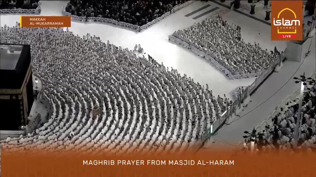 Thousands of worshippers in white ihram garments stand shoulder-to-shoulder in neat rows, facing the Kaaba. The scene, broadcast live by Islam Channel, captures the Maghrib prayer at Masjid al-Haram in Makkah.