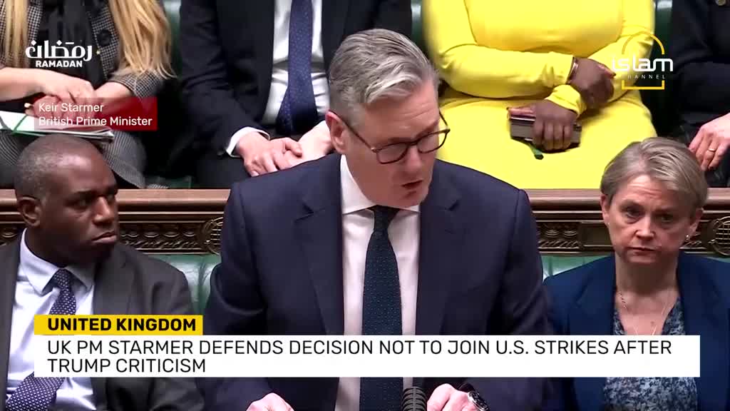 The Prime Minister speaks from the dispatch box, his voice amplified by the microphone. Across the chamber, MPs listen intently, some with stern expressions.