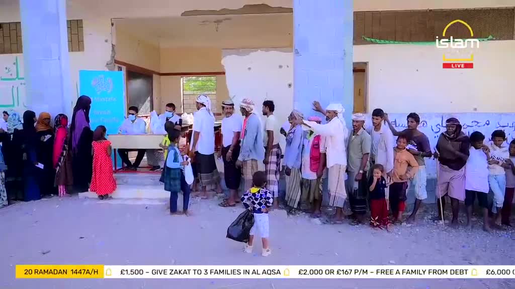 People are lining up outside a building, some holding bags. A young boy in a patterned shirt stands with a black plastic bag.