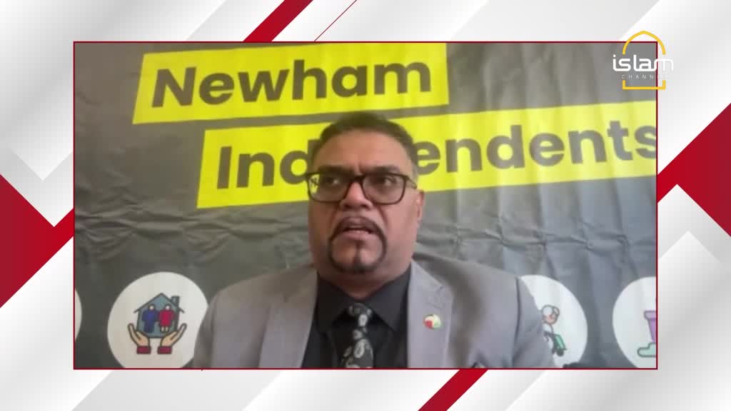 A man in a grey suit speaks directly to the camera, his voice clear. Behind him, a banner proclaims "Newham Independents" in bold yellow lettering.