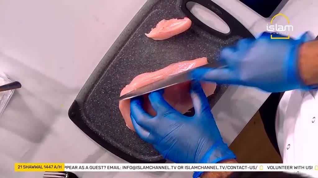 Hands in blue gloves carefully slice a raw chicken breast on a dark cutting board. A small piece of chicken has already been separated. Hands in blue gloves carefully slice a raw chicken breast on a dark cutting board. A small piece of chicken has already been separated.