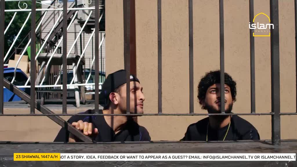 Two young men peer through a metal fence, their faces tilted upwards. The Islam Channel logo is visible in the upper right corner.