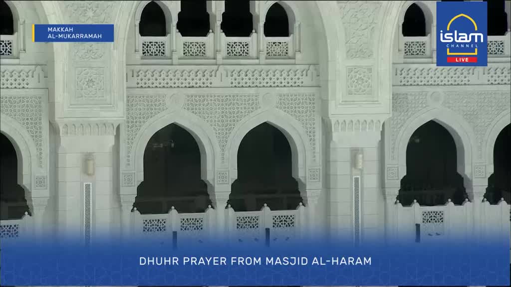 The white marble of Masjid Al-Haram rises before me, its intricate carvings catching the light. Islam Channel's live broadcast indicates this is the Dhuhr prayer from Makkah Al-Mukarramah.