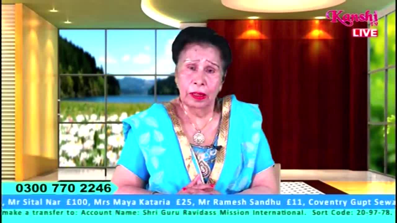 A woman in a blue top sits in front of a Kanshi TV backdrop, speaking directly to the camera. Below, a green bar displays a phone number and donation information for the United Kingdom.
