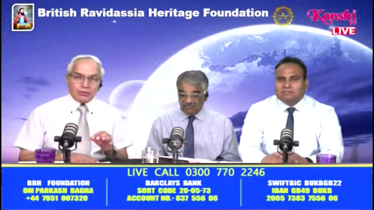 Three men in shirts and ties sit at a table, each with a microphone, on a Kanshi TV broadcast. The man on the left gestures with his hand while speaking, and the bottom of the screen displays contact and banking information for the British Ravidassia Heritage Foundation.
