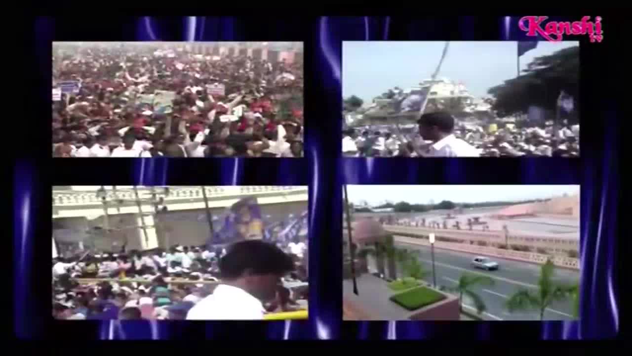 Kanshi TV is showing a montage of scenes, including a large crowd waving signs and a car driving on a wide road. The screen is framed by a blue, wavy background.
