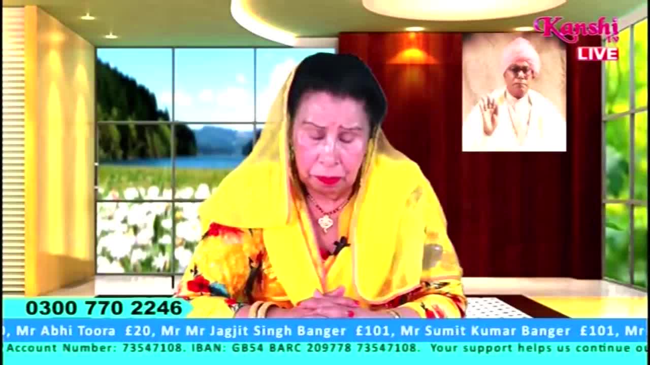 A woman in a yellow headscarf and jacket is seated, looking down with her hands clasped. The Kanshi TV logo is visible, along with a phone number and donation information at the bottom of the screen.
