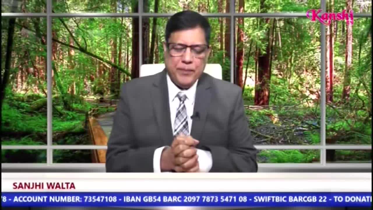 A man in a suit sits at a desk on Kanshi TV, his hands clasped in front of him. Behind him, a window displays a forest scene, and the show's name is displayed at the bottom of the screen.
