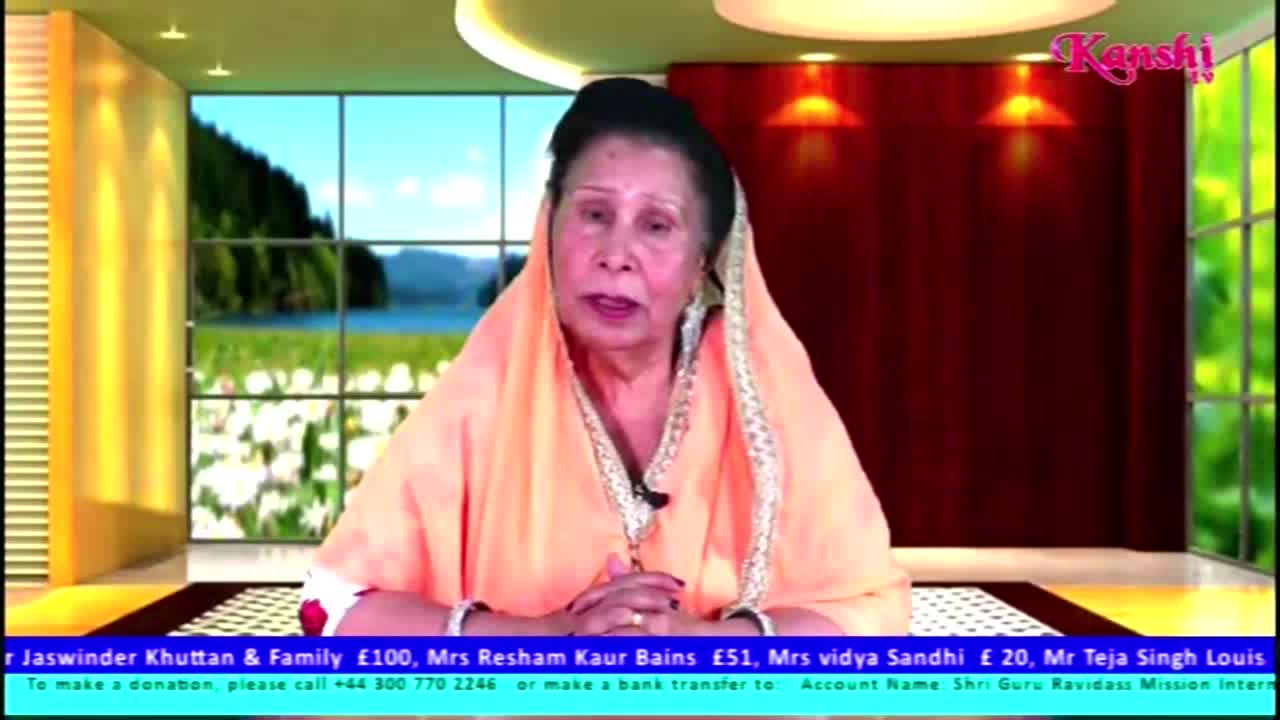A woman in a peach-colored headscarf speaks directly to the camera on Kanshi TV, her hands clasped in front of her. The backdrop shows a landscape scene, and a scrolling text at the bottom lists donors and contact information from the United Kingdom.

