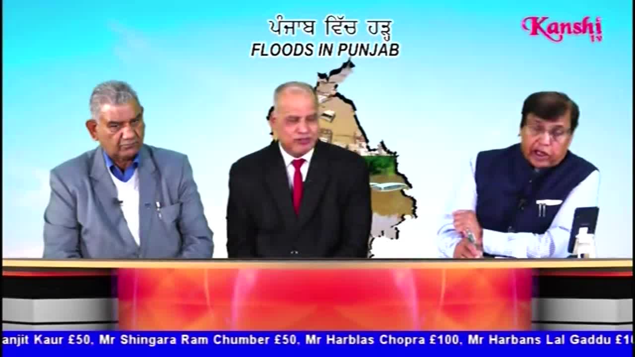 Three men sit at a table on a Kanshi TV set, discussing "Floods in Punjab" in front of a map of the region. The man in the middle gestures as he speaks, while the others listen intently.
