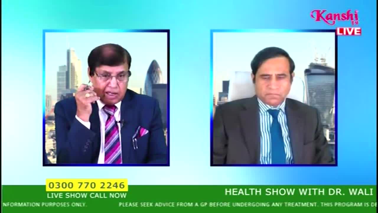 Two men in suits are on a Kanshi TV broadcast, with a London skyline visible behind one of them. The man on the left gestures with a pen while speaking, and the other listens attentively.
