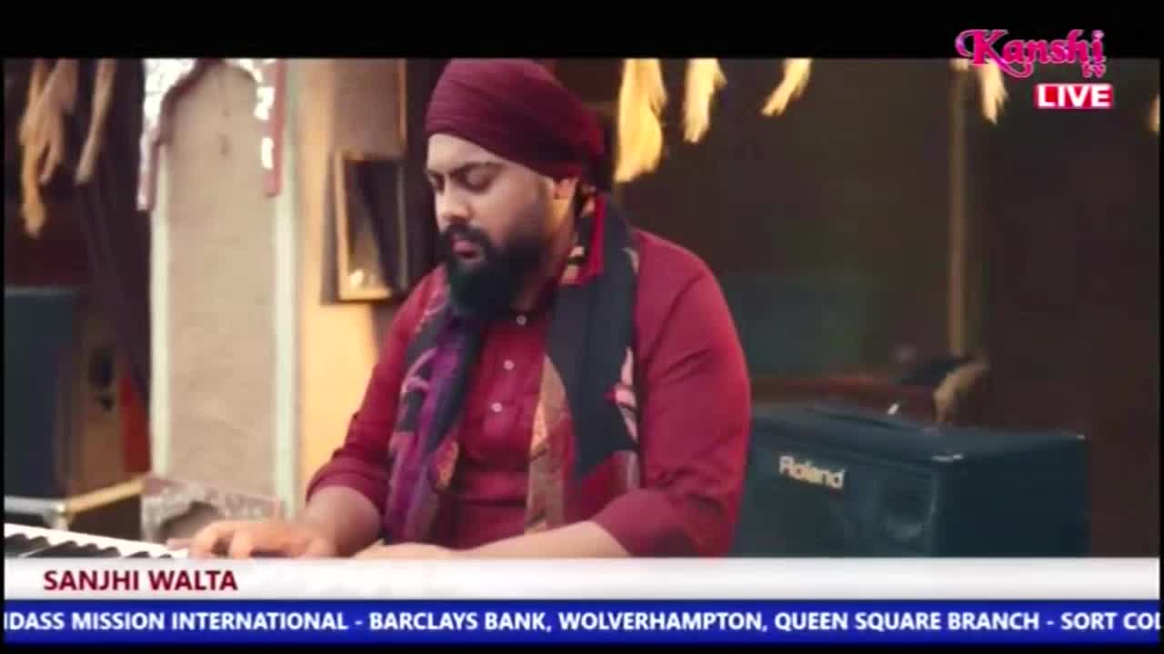A man wearing a turban and a scarf sits at a keyboard, his fingers poised above the keys. The Kanshi TV logo is visible in the upper right corner.
