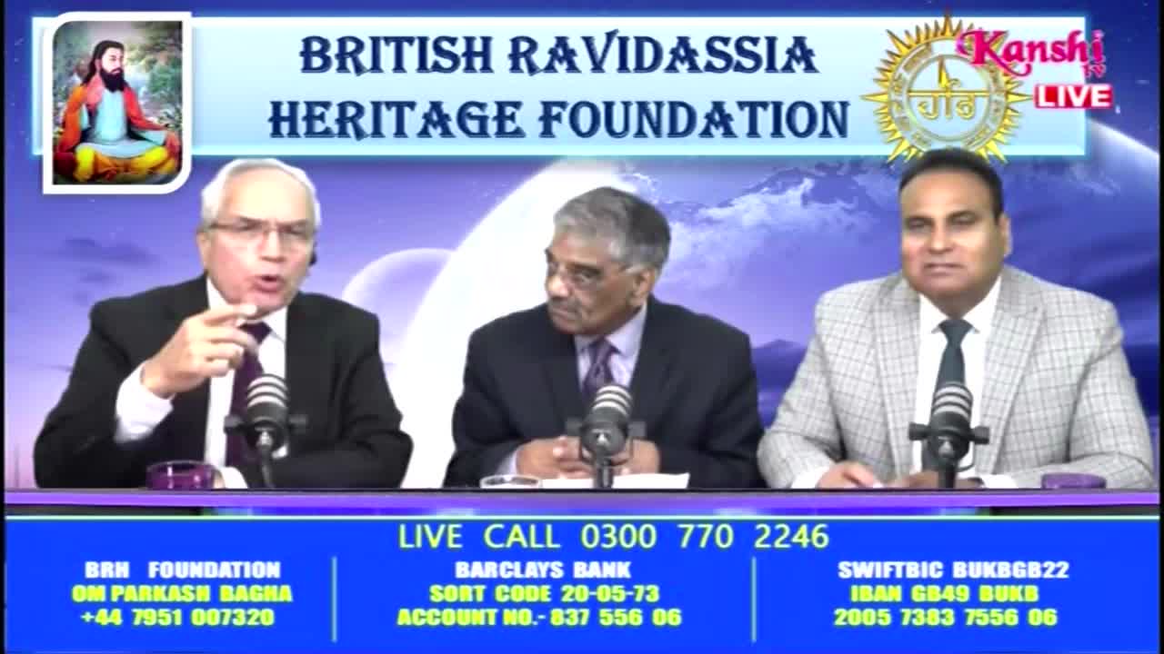 Three men sit behind a desk, each with a microphone in front of them. The man on the left gestures with his hand while speaking, and the Kanshi TV logo is visible in the corner.
