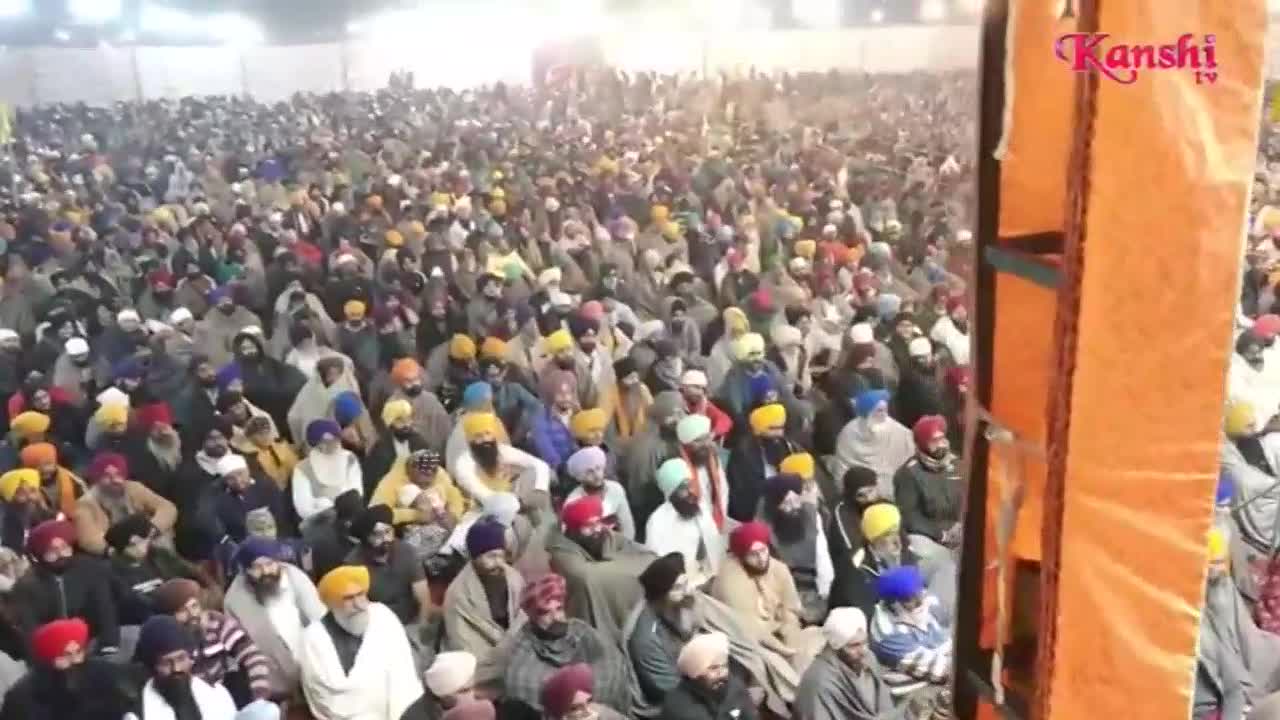 A large crowd, many wearing turbans, fills the space, and the Kanshi TV logo is visible in the corner. The atmosphere is calm, with people sitting and listening.
