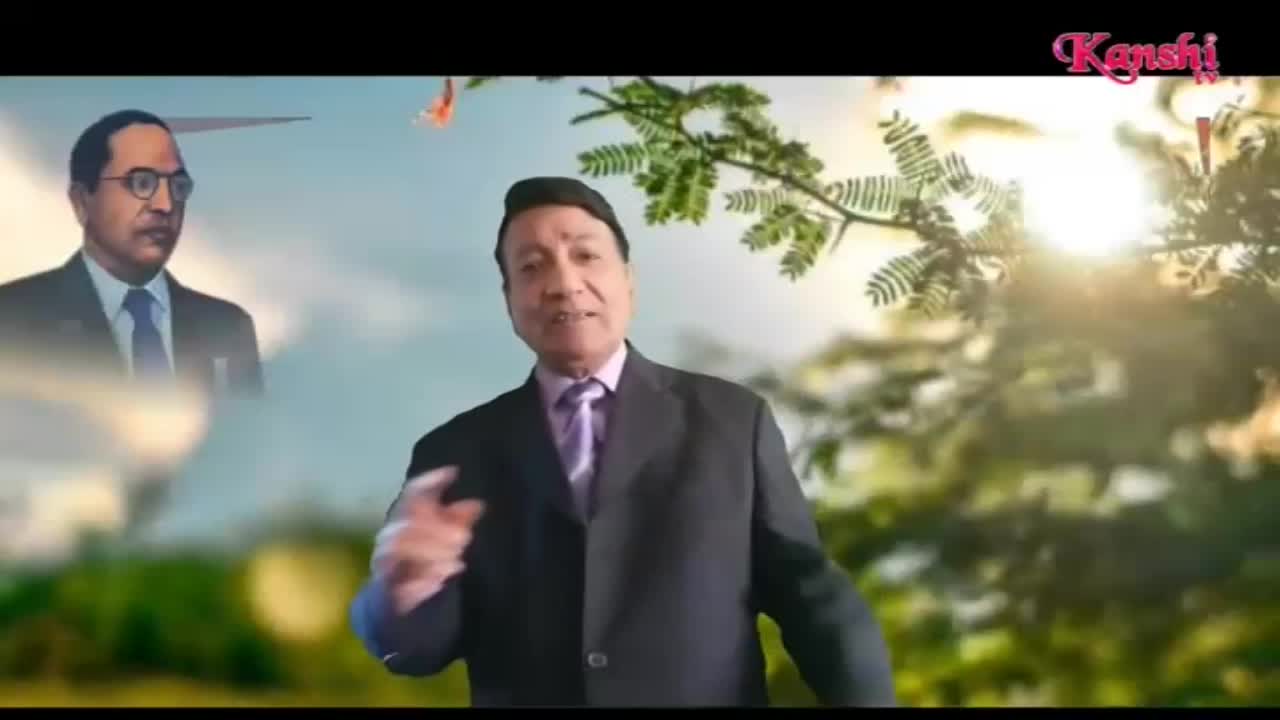 A man in a suit gestures with his right hand as he speaks, while a portrait of a man in glasses floats in the background. The Kanshi TV logo is visible in the top right corner.
