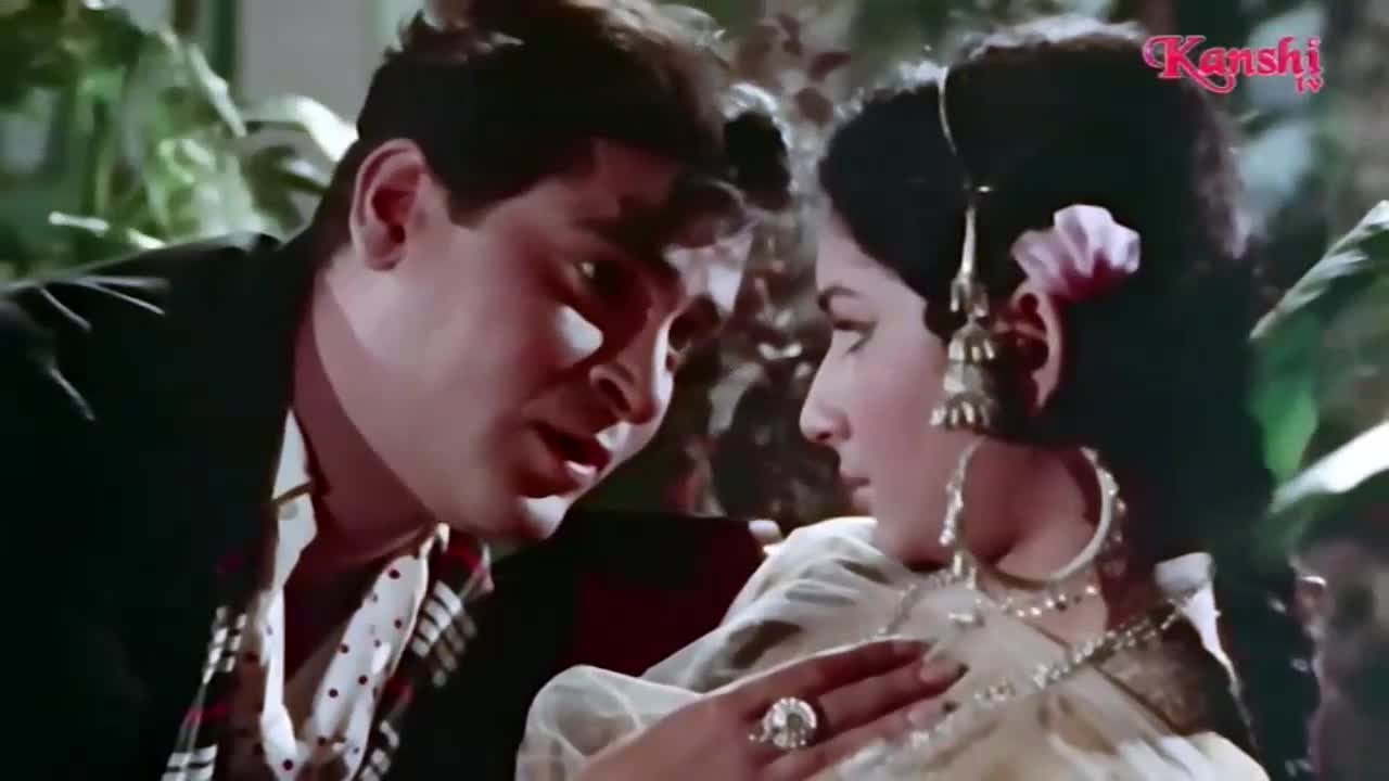 A man leans in close to a woman, his expression intense. She looks away, her elaborate jewelry catching the light.