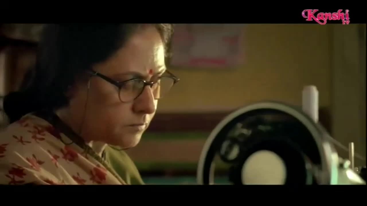 A woman intently focuses on her sewing machine, her glasses reflecting the light. The Kanshi TV logo appears in the corner, hinting at the broadcast.