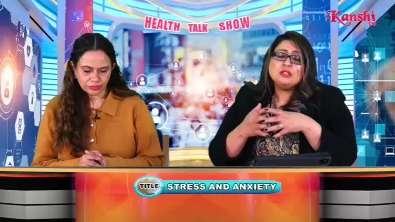 Two women sit at a desk, one speaking with her hands animated, the other looking down. A banner across the bottom of the screen reads "TITLE STRESS AND ANXIETY."