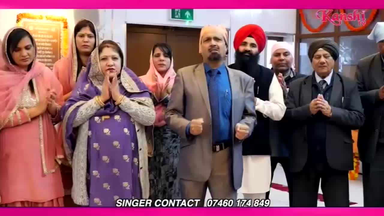 A group of people stand with hands pressed together in prayer. The man in the centre, wearing a grey suit, has his fists clenched as he sings.