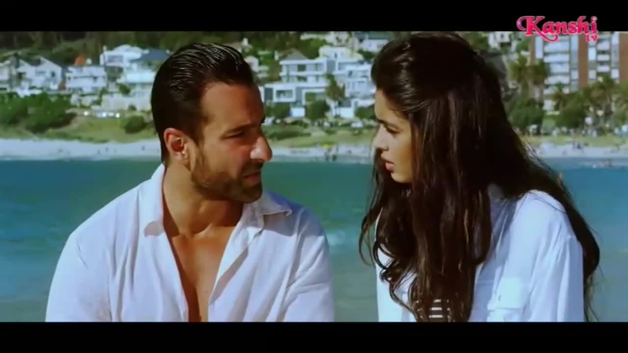 A man in a white shirt looks intently at a woman beside him. They are seated with a bright blue ocean and a distant coastline behind them, a scene familiar from Kanshi TV productions.