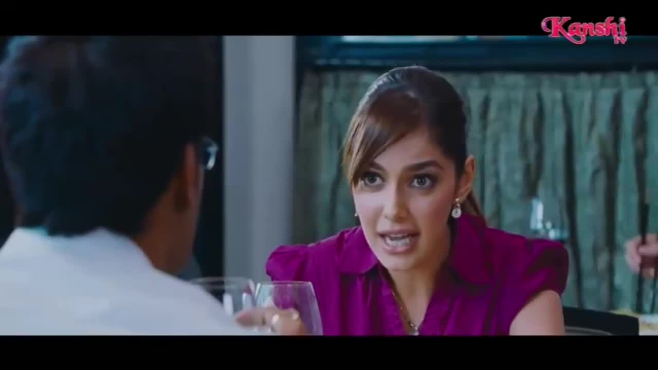 The woman in the purple top is speaking animatedly, her eyes wide. She gestures with her hands as if making a point to the man across from her.