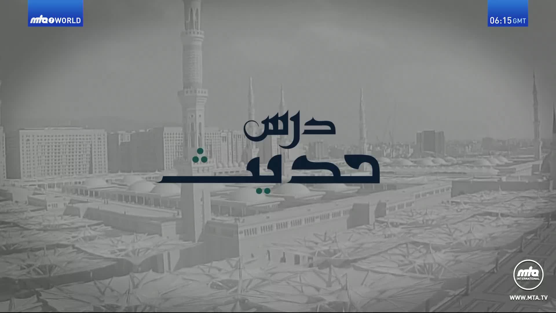 The MTA1 World logo and time display in the top right corner. Below, a graphic in Arabic script sits atop a faded image of a large mosque complex.

