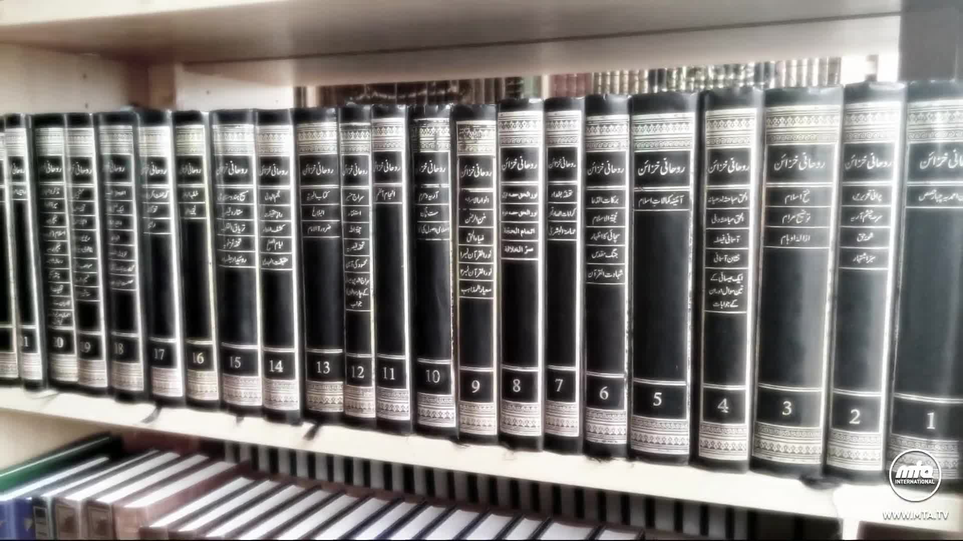 A row of black books with white lettering lines the shelf. The MTA1 World logo is visible on the bottom right corner of the shelf.
