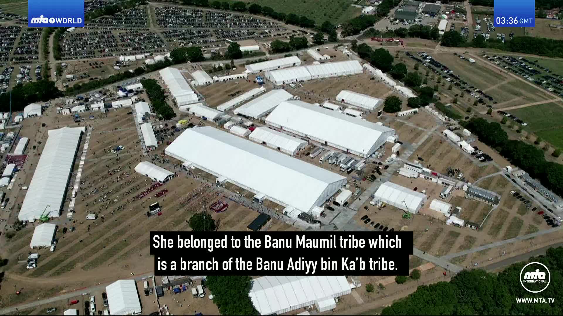 A vast field in the UK is covered with rows of white marquees, resembling a temporary city. Cars are parked in orderly lines on the periphery, and people mill about between the structures. A vast field in the UK is covered with rows of white marquees, resembling a temporary city. Cars are parked in orderly lines on the periphery, and people mill about between the structures.