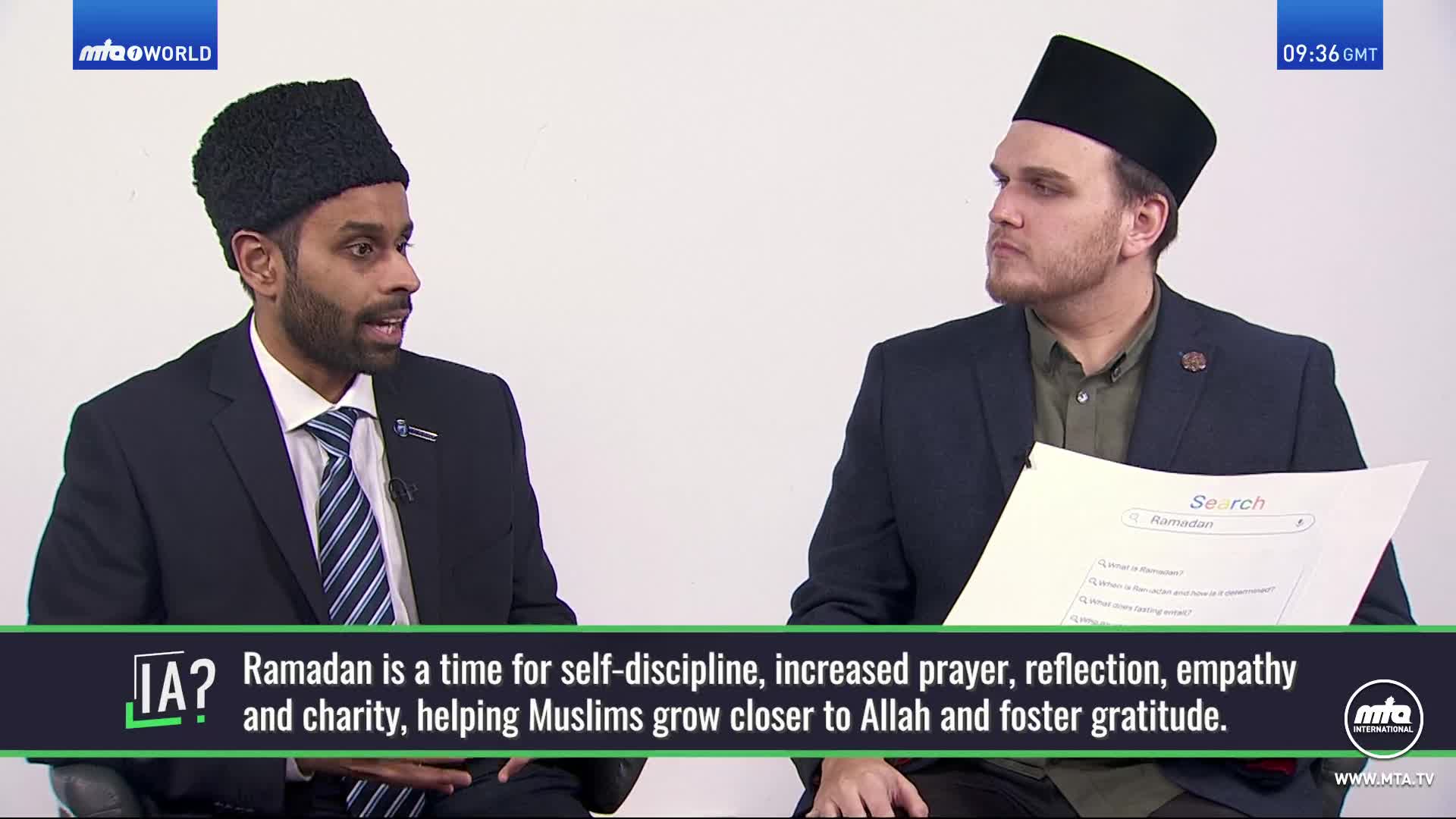 Two men sit facing each other, one speaking animatedly while the other listens, holding a piece of paper with a search query for "Ramadan." A graphic at the bottom of the screen displays text about the significance of Ramadan.