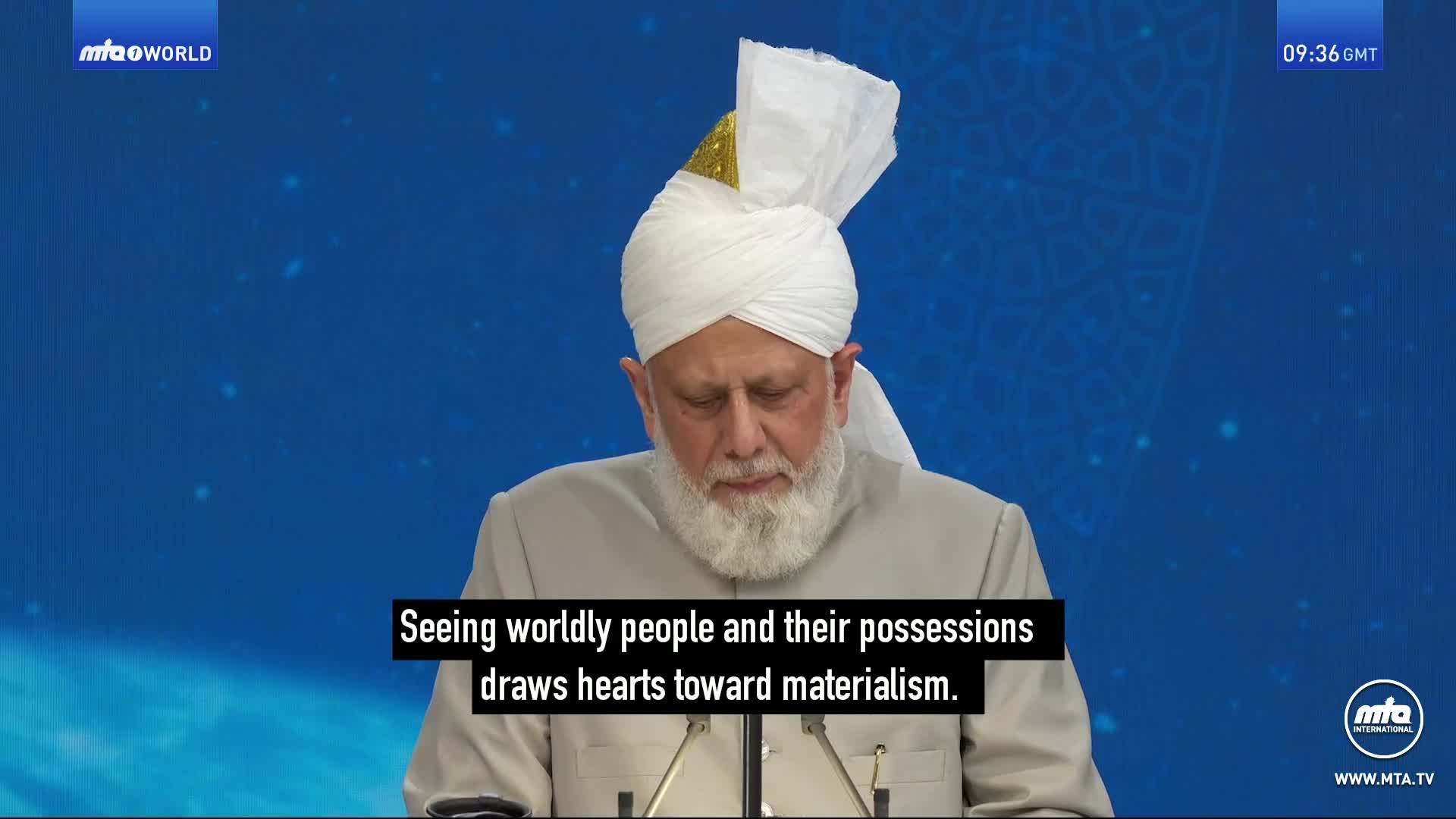 A man in a white turban speaks at a podium. The MTA World logo appears in the upper left corner.