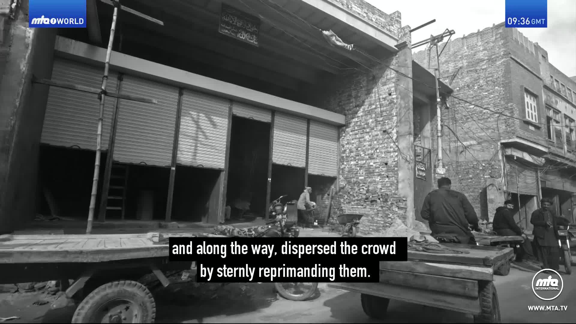 A man in a light-colored shirt stands by a cart, his back to us. Two other men sit on benches near a motorcycle, their faces obscured.