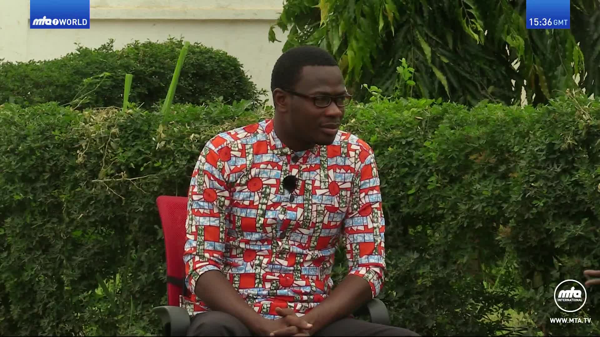 A man in a colourful shirt sits in a red chair, looking off to the side. The MTA World logo appears in the top left corner.