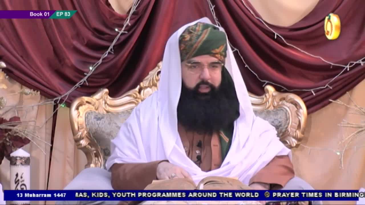 A man in a turban and white shawl sits in an ornate chair, reading from a book. The Noor TV logo is visible, and the scene appears to be a broadcast from the United Kingdom.
