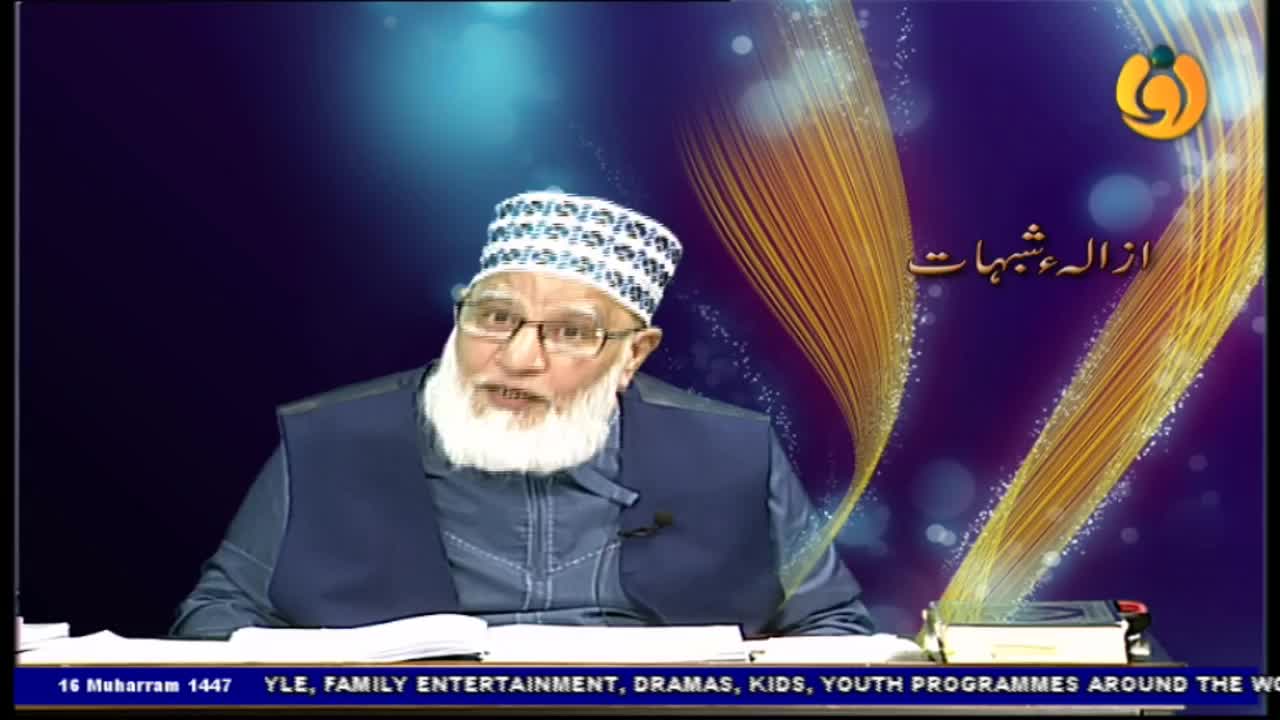 A man with a long white beard and glasses speaks animatedly, his mouth open. He's wearing a patterned cap and a dark blue vest, likely on a Noor TV program from the United Kingdom.
