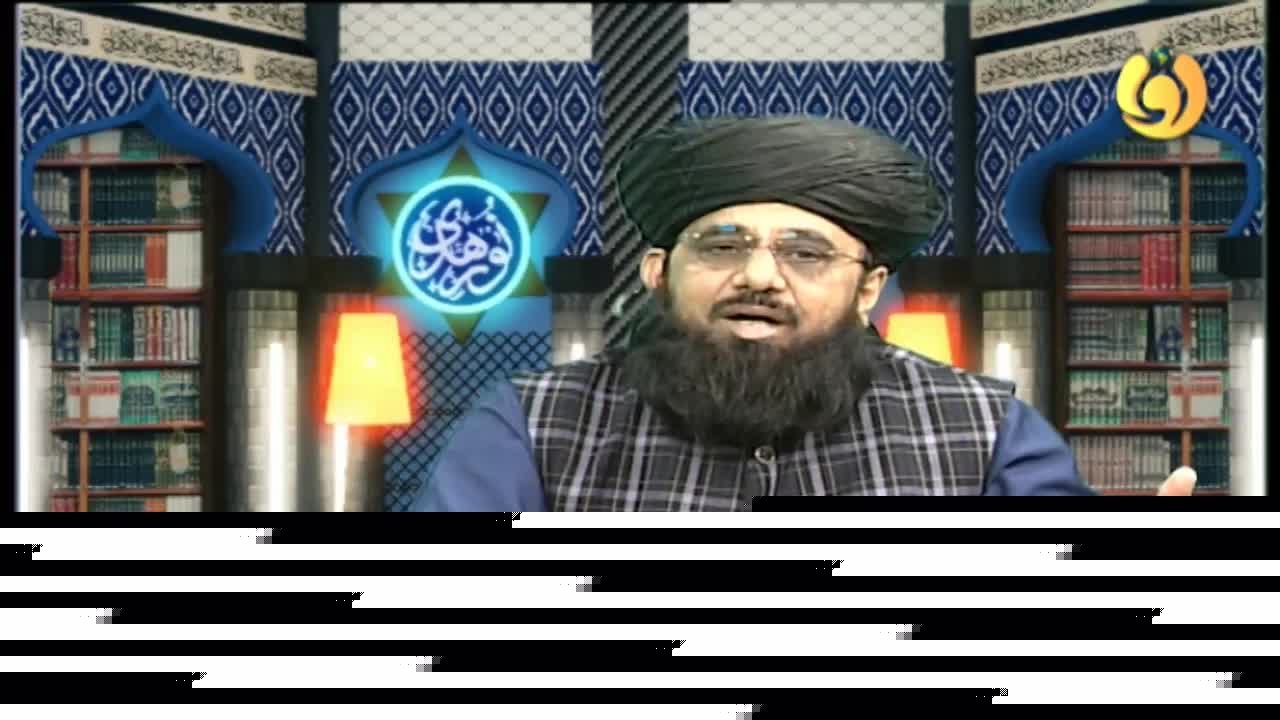 A man in a black turban and glasses gestures with his right hand, speaking on Noor TV. Behind him, a stylized backdrop includes bookshelves and a glowing emblem.
