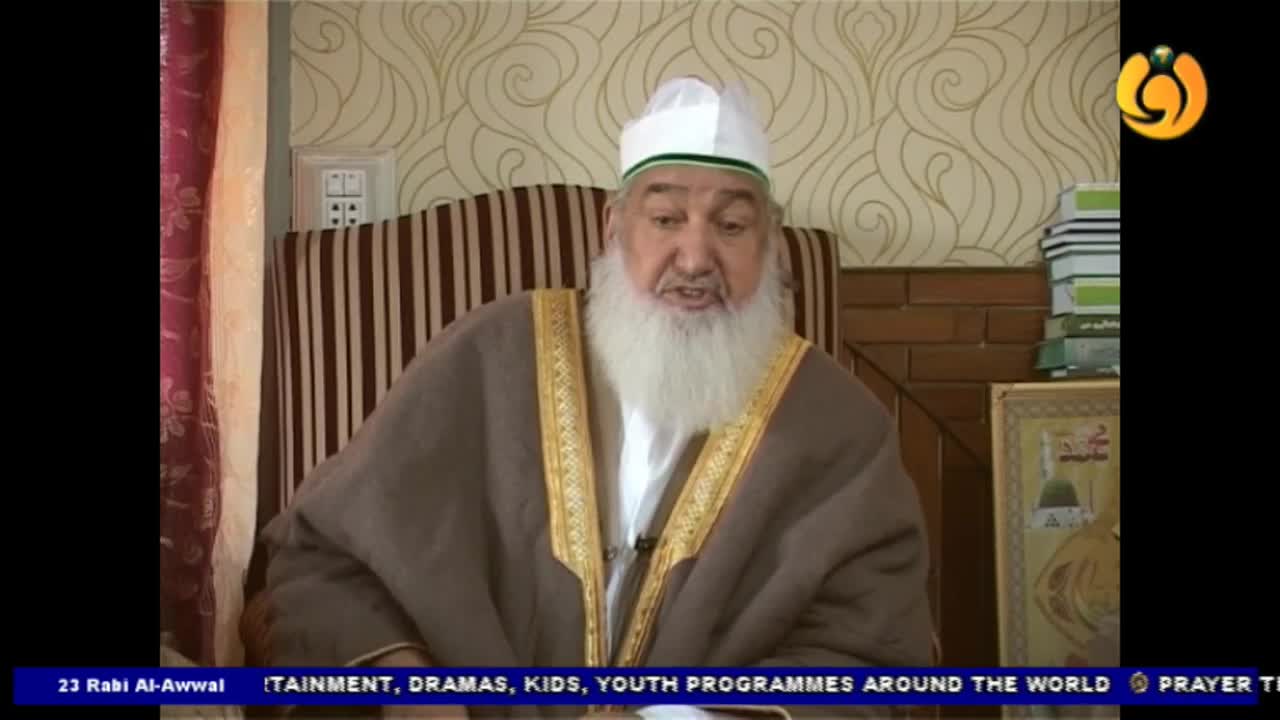 A man in a white cap and long white beard is speaking, his hands gesturing. The Noor TV logo is visible in the corner, and the lower third of the screen has a blue banner with text.

