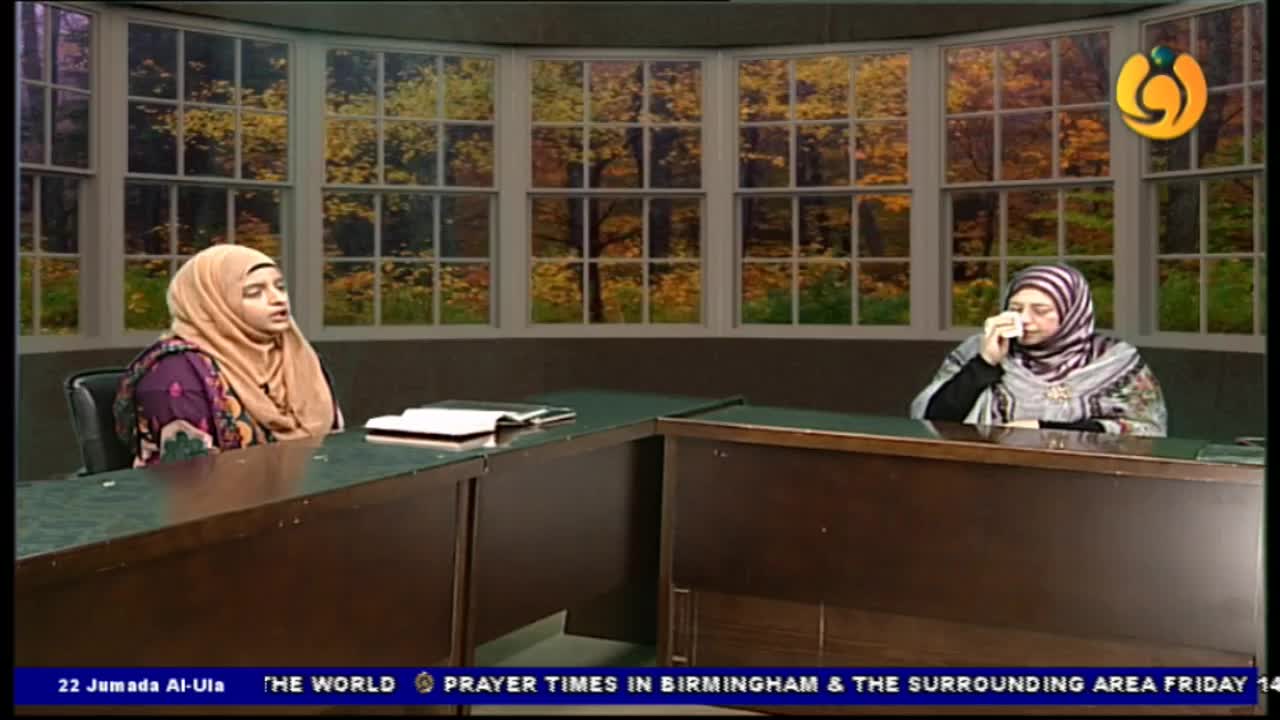 Two women in headscarves sit behind a desk, facing each other on a Noor TV set. One speaks, while the other holds a tissue to her face.
Two women in headscarves sit behind a desk, facing each other on a Noor TV set. One speaks, while the other holds a tissue to her face.