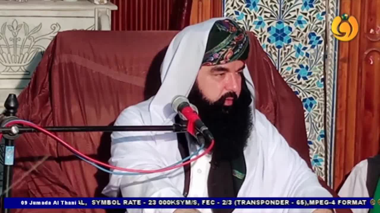 A man with a long, dark beard speaks into a microphone, his face framed by a white head covering. The Noor TV logo is visible in the corner, and a screen displays technical information at the bottom.
