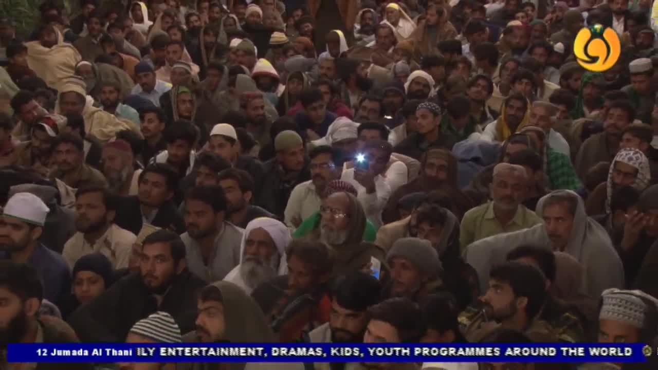 A large crowd of men, many in traditional head coverings, are packed closely together. The Noor TV logo is visible in the corner, and a few people are holding up phones.

