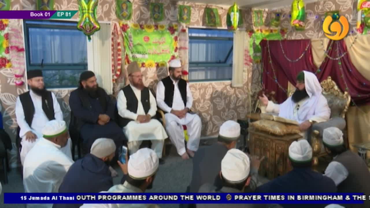 A robed man gestures while reading from a book, seated on an ornate chair. Several men in white caps listen attentively, some holding phones.
