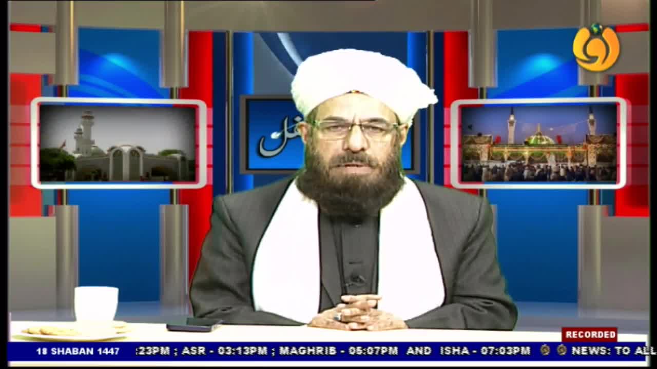 A man in a white turban and glasses sits at a desk in front of a screen displaying Islamic imagery. The Noor TV logo is visible in the corner.