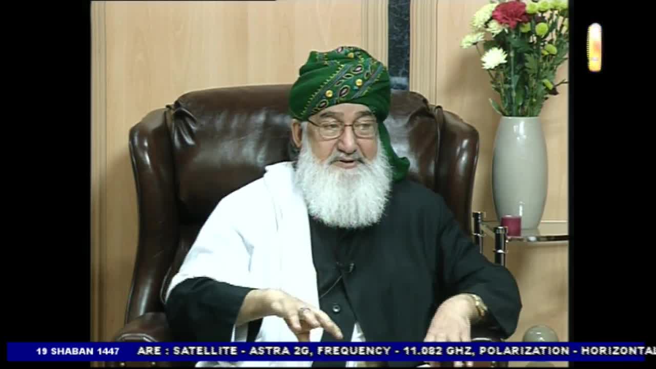 A man in a green turban and glasses is speaking. He gestures with his hands while seated in a leather chair.