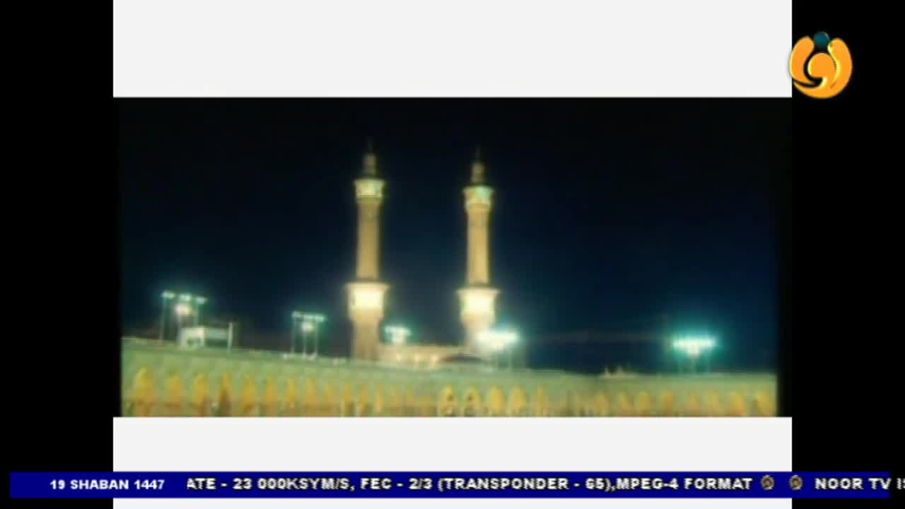 Two tall, illuminated minarets pierce the night sky above a long, low building. The scene is broadcast on Noor TV, a channel familiar to many in the UK.