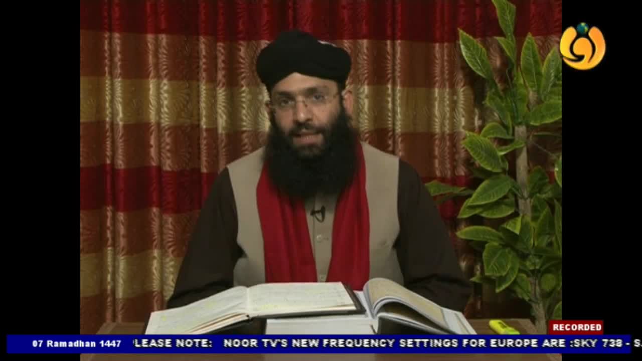 A man in a black turban and red scarf speaks directly to the camera, his hands resting on open books. The Noor TV logo is visible in the corner, indicating a broadcast from the UK. A man in a black turban and red scarf speaks directly to the camera, his hands resting on open books. The Noor TV logo is visible in the corner, indicating a broadcast from the UK.