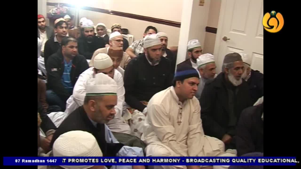 A group of men, many wearing white kufis, are seated on the floor. The Noor TV logo appears in the top right corner. A group of men, many wearing white kufis, are seated on the floor. The Noor TV logo appears in the top right corner.